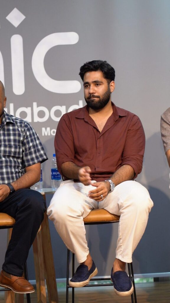 Panelists seated on stools on stage