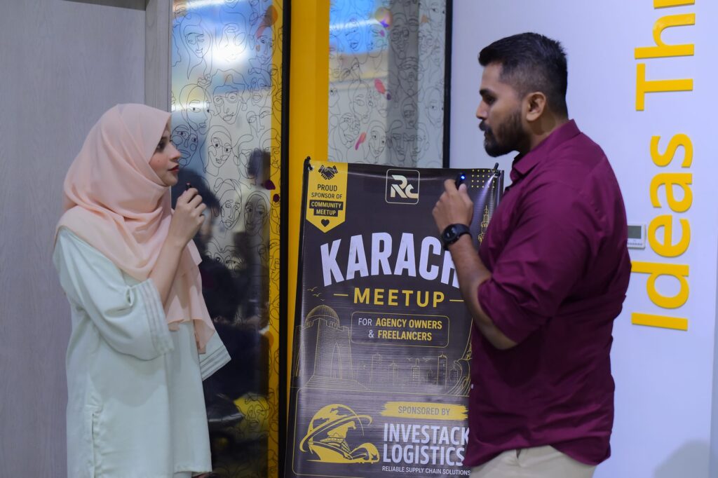 Two speakers talking beside the Karachi meetup banner