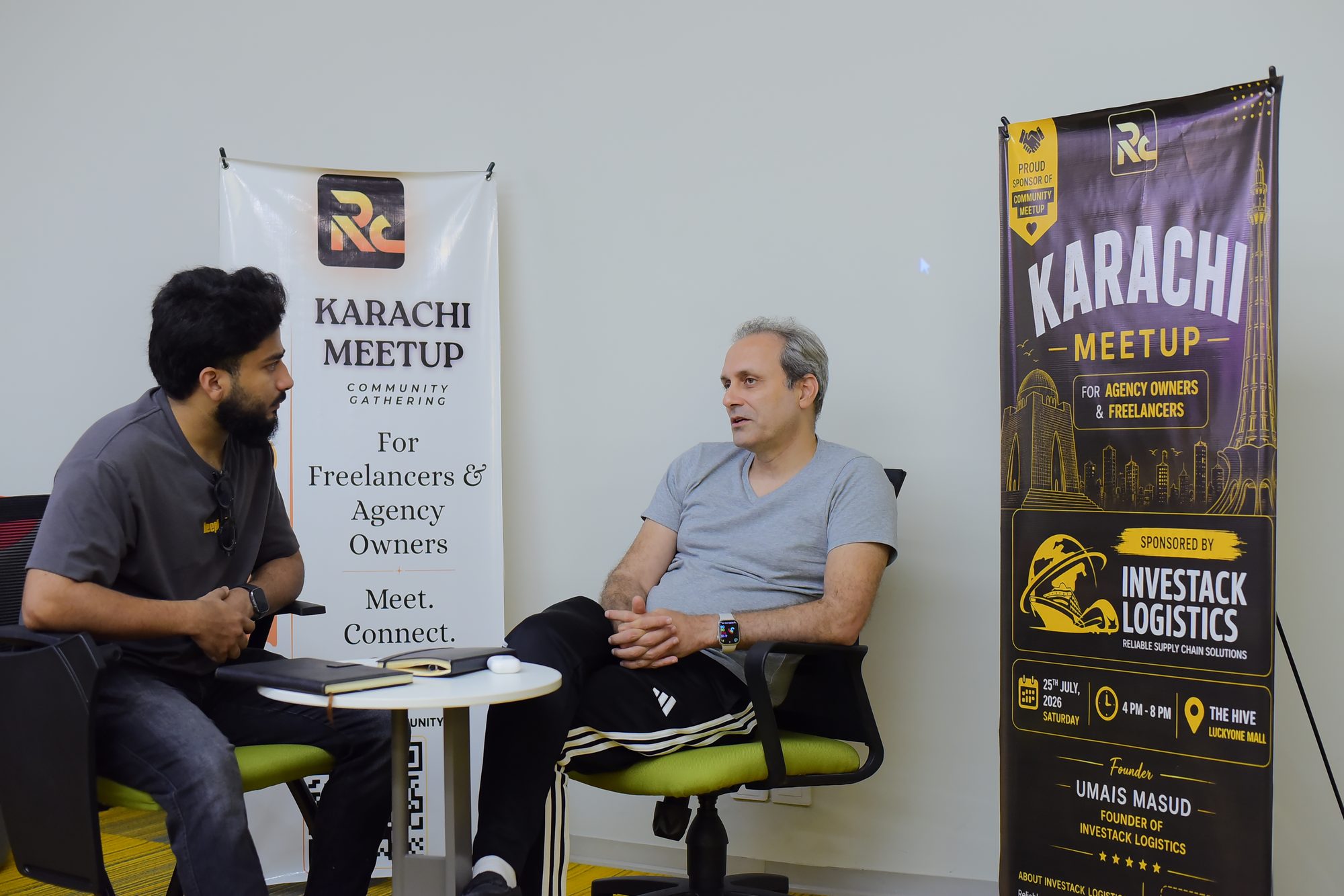Two speakers seated in front of the Karachi meetup banners
